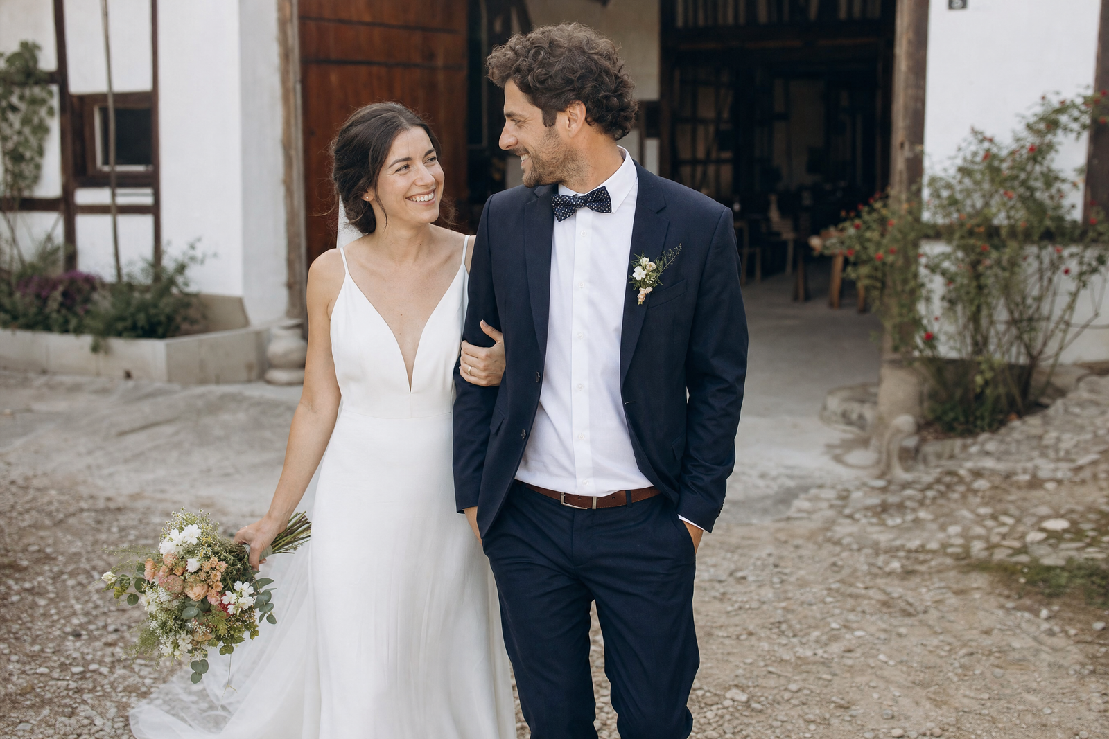 Ein Hochzeitspaar geht gemeinsam über einen Hof.